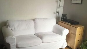 A white sofa in a living room with a wooden coffee table, a small plant, and a painting on the wall. - Paris 15, Joli 2 Pièces 1/4h à Pieds Tour Eiffel (Paris)