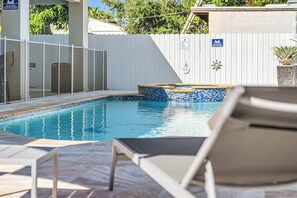 A swimming pool with a tiled edge, a lounge chair, and a fenced area with a sign. - Tropical 3BR Miami Getaway – Pool & Prime Location (Miami)