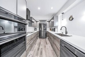 A modern kitchen with a central island, stainless steel appliances, and a minimalist design. - Tropical 3BR Miami Getaway – Pool & Prime Location (Miami)