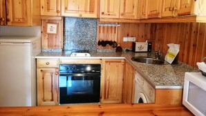 Una cocina con armarios de madera, lavavajillas, horno, microondas y encimera de granito.