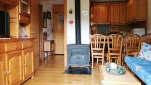 Una sala de estar con chimenea, muebles de madera y una zona de cocina con armarios de madera.