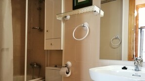 Un baño con inodoro, lavabo, ducha y espejo.
