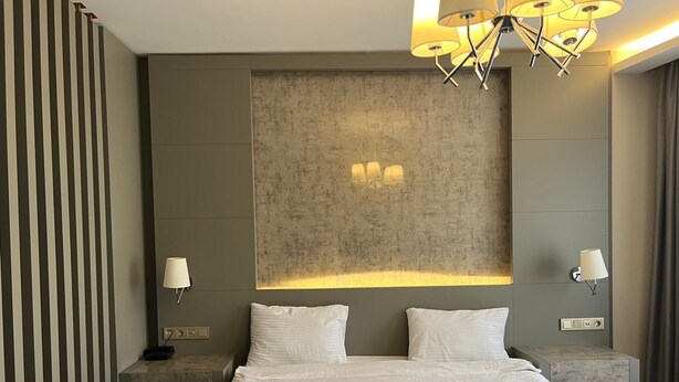A modern hotel room with a large bed, two bedside tables, and a unique textured wall panel. - Acar Suite Hotel (Istanbul)