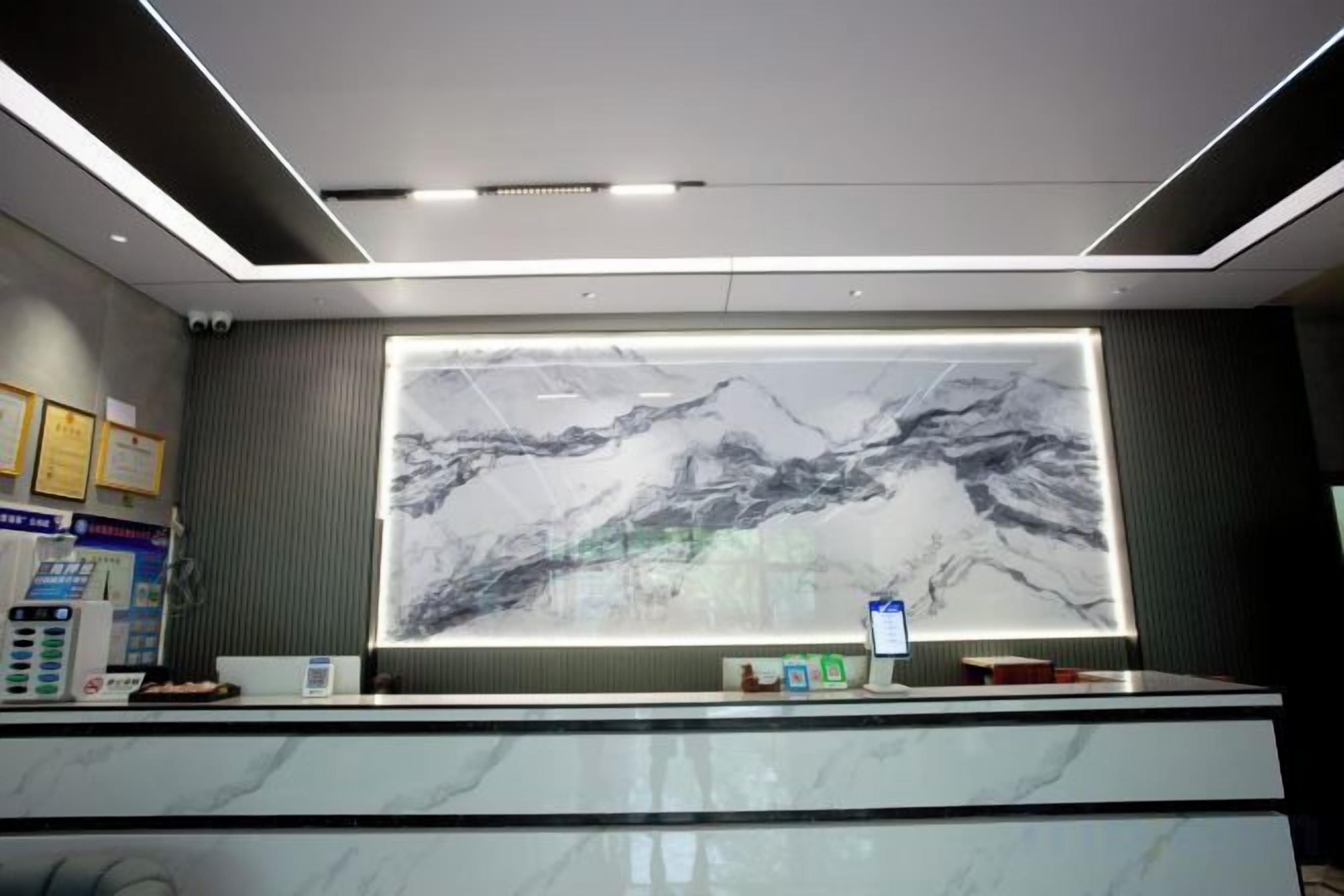 A reception desk with a large framed picture of mountains, a computer, and a phone.