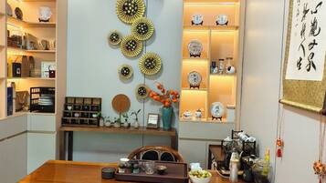 A dining area with a wooden table, decorative wall art, and shelves with various items.