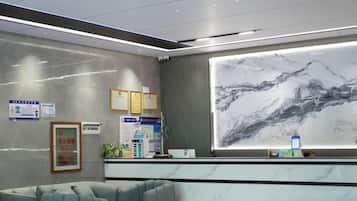 Una zona de recepción con mostrador de mármol, certificados enmarcados y un mural grande en la pared.