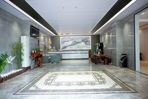 A hotel lobby with a reception desk, seating area, and a large decorative rug. - Mancheng Boutique Hotel (Mengla)