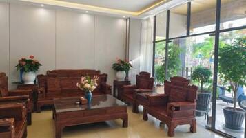 A hotel lobby with a sofa set, armchairs, a coffee table, and potted plants.