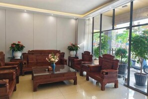 A hotel lobby with a sofa set, armchairs, a coffee table, and potted plants. - Mancheng Boutique Hotel (Mengla)