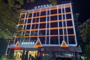 A multi-story hotel with a modern facade, illuminated signage, and a prominent entrance. - Mancheng Boutique Hotel (Mengla)