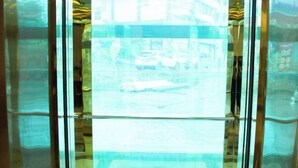 An elevator with a glass panel, reflecting a street scene with cars and buildings. - Mancheng Boutique Hotel (Mengla)