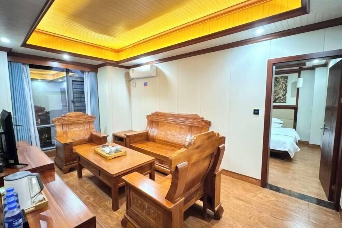 A hotel room with a wooden sofa set, a small table, a TV, and a bed.