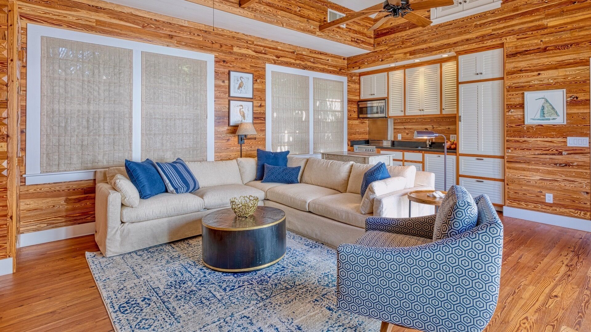 Una sala de estar acogedora con un sofá color beige, cojines azules, una mesa de centro redonda y una alfombra estampada.