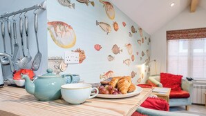 A kitchen with a striped countertop, a teapot, a cup, and a plate with croissants and grapes. - The Fish Store, Aldeburgh (Aldeburgh)