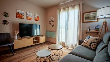 Un salon équipé d’un téléviseur à écran plat, d’un canapé, d’une table basse et d’une lampe.