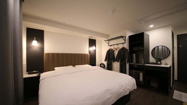 Une chambre d’hôtel moderne avec un grand lit, une table de chevet et une armoire intégrée.