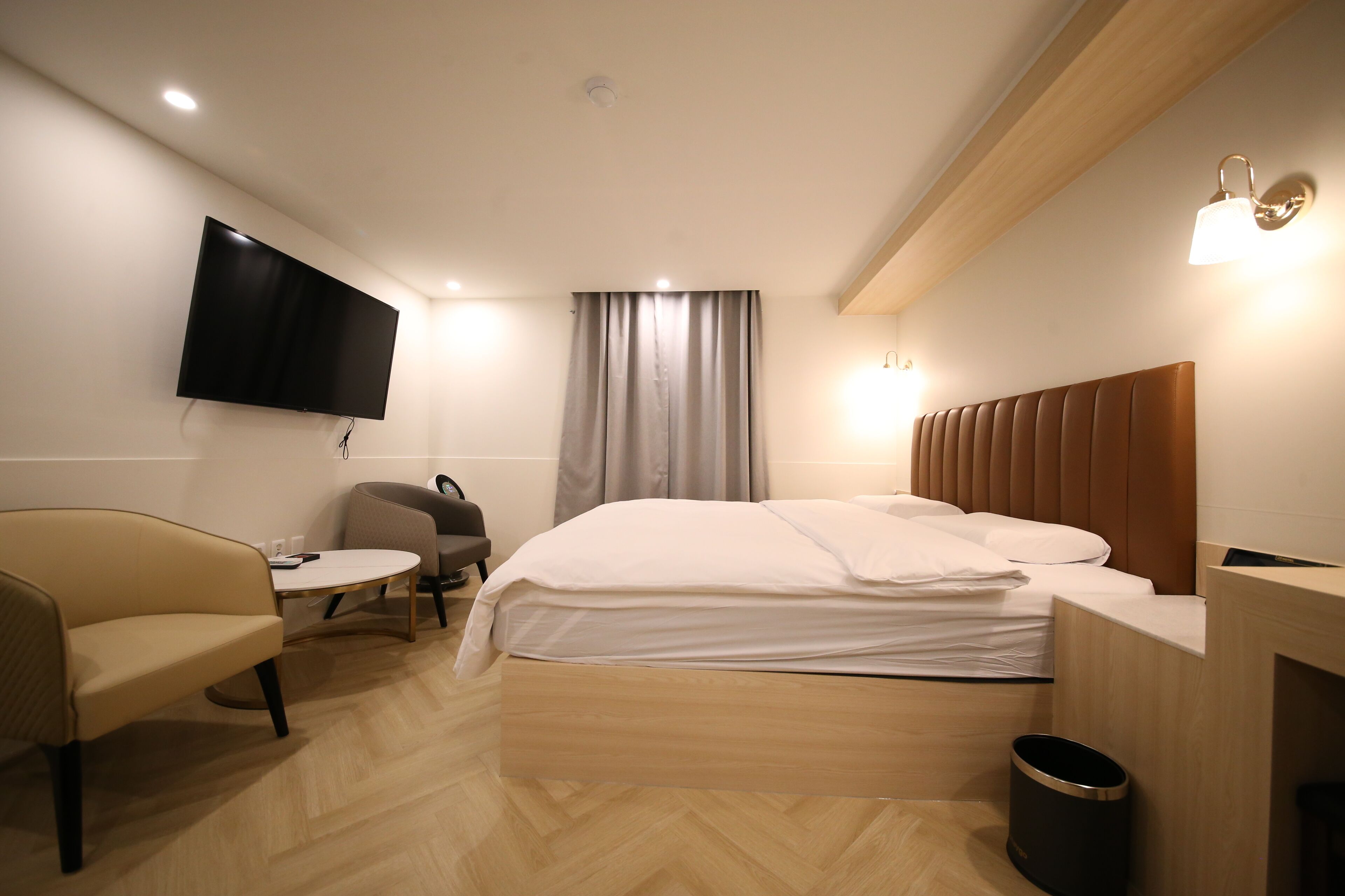 Une chambre d’hôtel équipée d’un lit, d’un bureau, d’une chaise, d’un téléviseur fixé au mur et d’une fenêtre avec des rideaux.