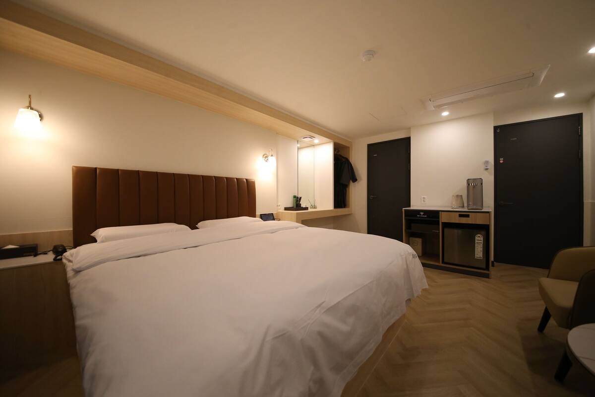 Una habitación de hotel con una cama grande, un escritorio con computadora, un armario y una zona de estar.