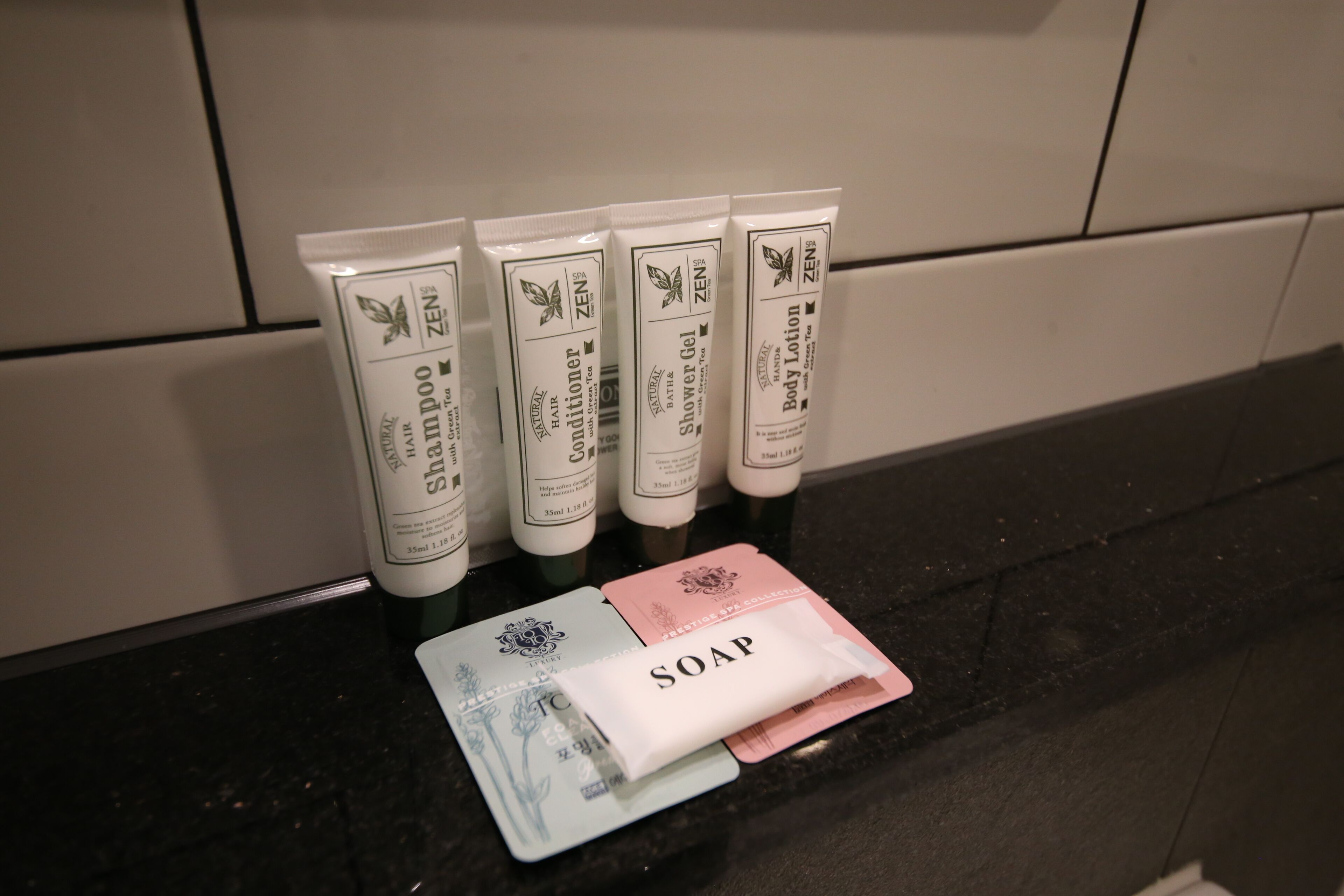 A bathroom counter with Zen brand toiletries including shampoo, conditioner, shower gel, and body lotion.