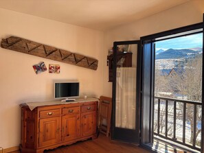 Una habitación con un armario de madera, un televisor y vistas a través de un ventanal.