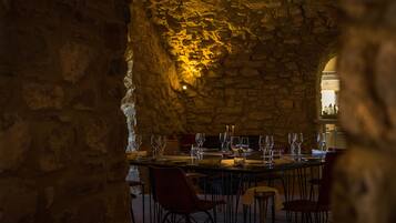 A stone-walled interior with a long dining table set for a meal.