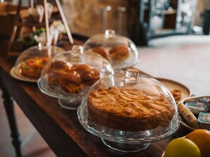 A buffet table with various food items covered in glass domes, including pastries and bread.