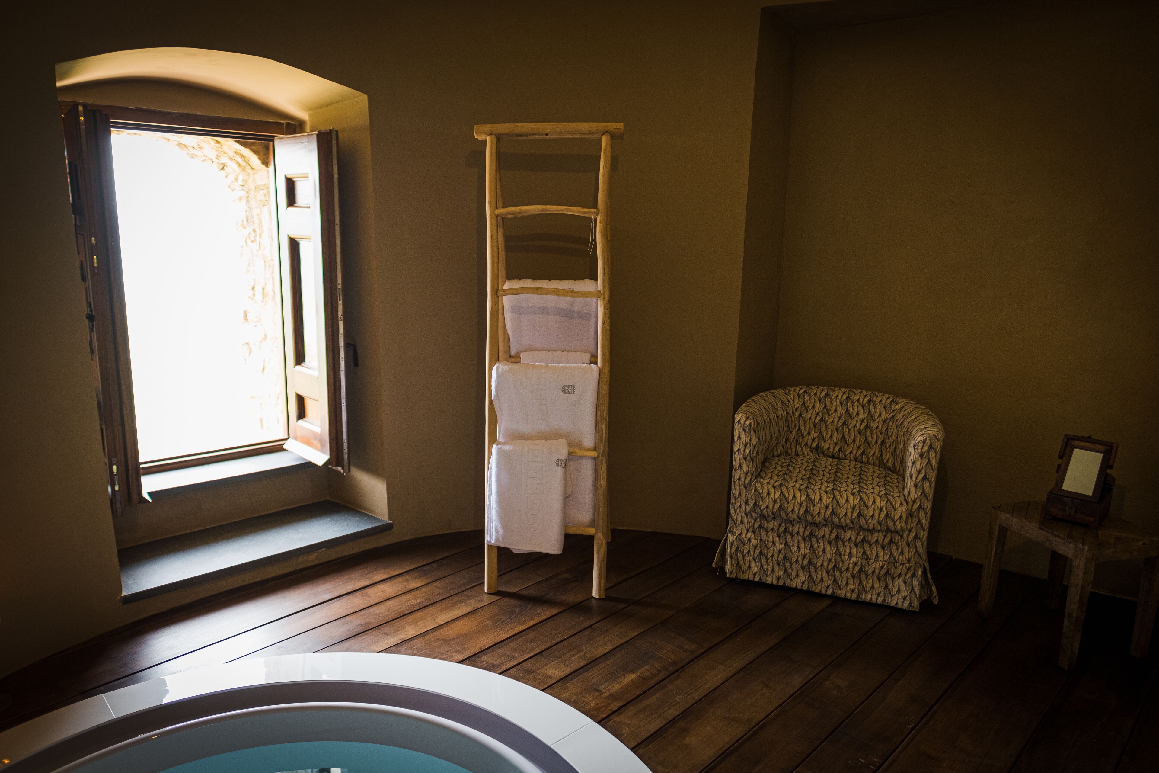 A room with a wooden ladder, a patterned chair, and a bathtub.