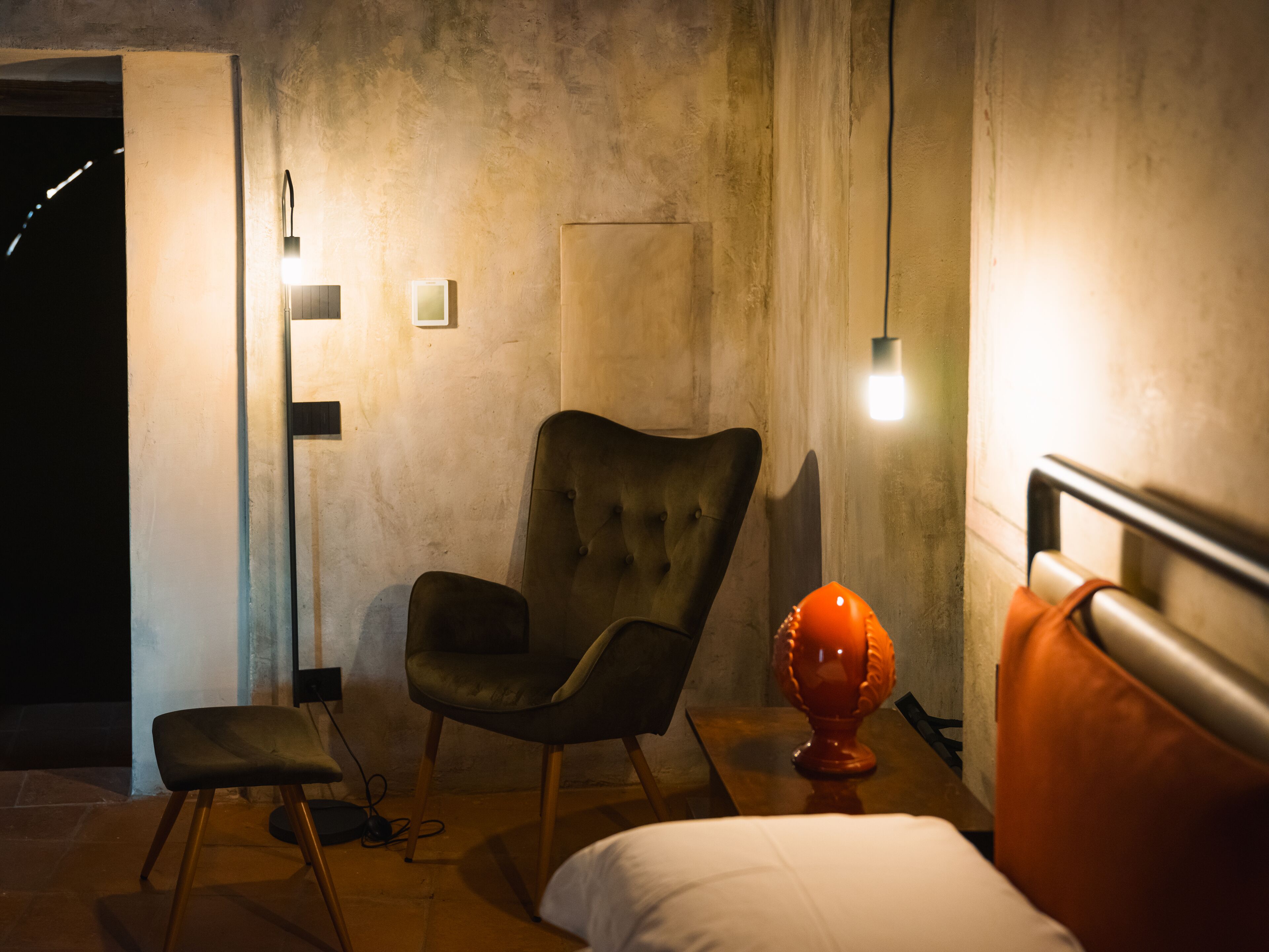 Ein Zimmer mit einem Bett, einem Sessel, einem Tisch und einer Lampe.