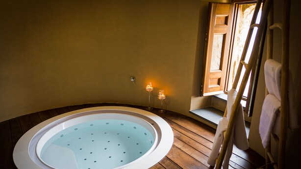 A hot tub in a wooden-floored room with a window and a towel rack. - Castello di Rocca Cilento (Lustra)