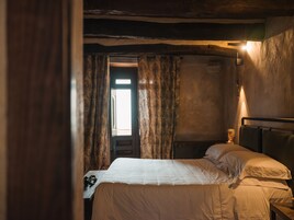 A bedroom with a bed, curtains, a window, and a wall-mounted light fixture.