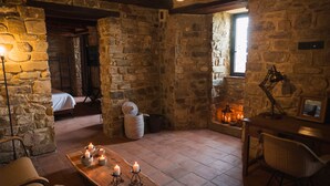 A stone-walled room with a wooden table, candles, and a bed in the background. - Castello di Rocca Cilento (Lustra)