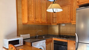 Une cuisine équipée de meubles en bois, d’un four à micro-ondes, d’un évier, d’une cuisinière et d’un réfrigérateur.