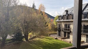 Un bâtiment en pierre doté de balcons, une cour verdoyante et des arbres.