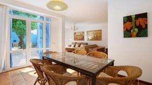 A dining area with wicker chairs, a glass table, and a chandelier. - Vacation Home "Villa Lucila" with Sea View, Garden & Wi-Fi (Corralejo)