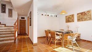 A dining area with a table and chairs, a staircase, and a hallway leading to a door. - Vacation Home "Villa Lucila" with Sea View, Garden & Wi-Fi (Corralejo)