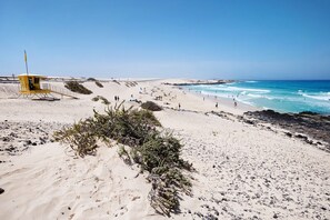 Une plage avec un poste de surveillance pour les sauveteurs, des dunes de sable et l’océan.