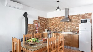 Cocina compacta con salpicadero de piedra, microondas integrado y refrigerador blanco.