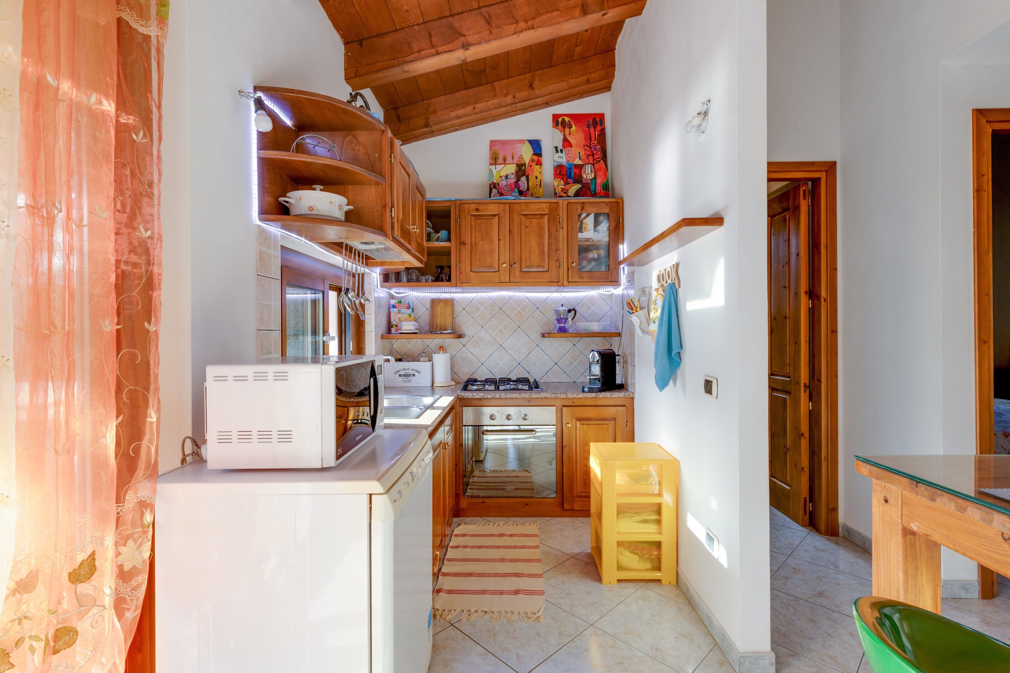 Cocina compacta con microondas, estufa, horno y armarios de madera.