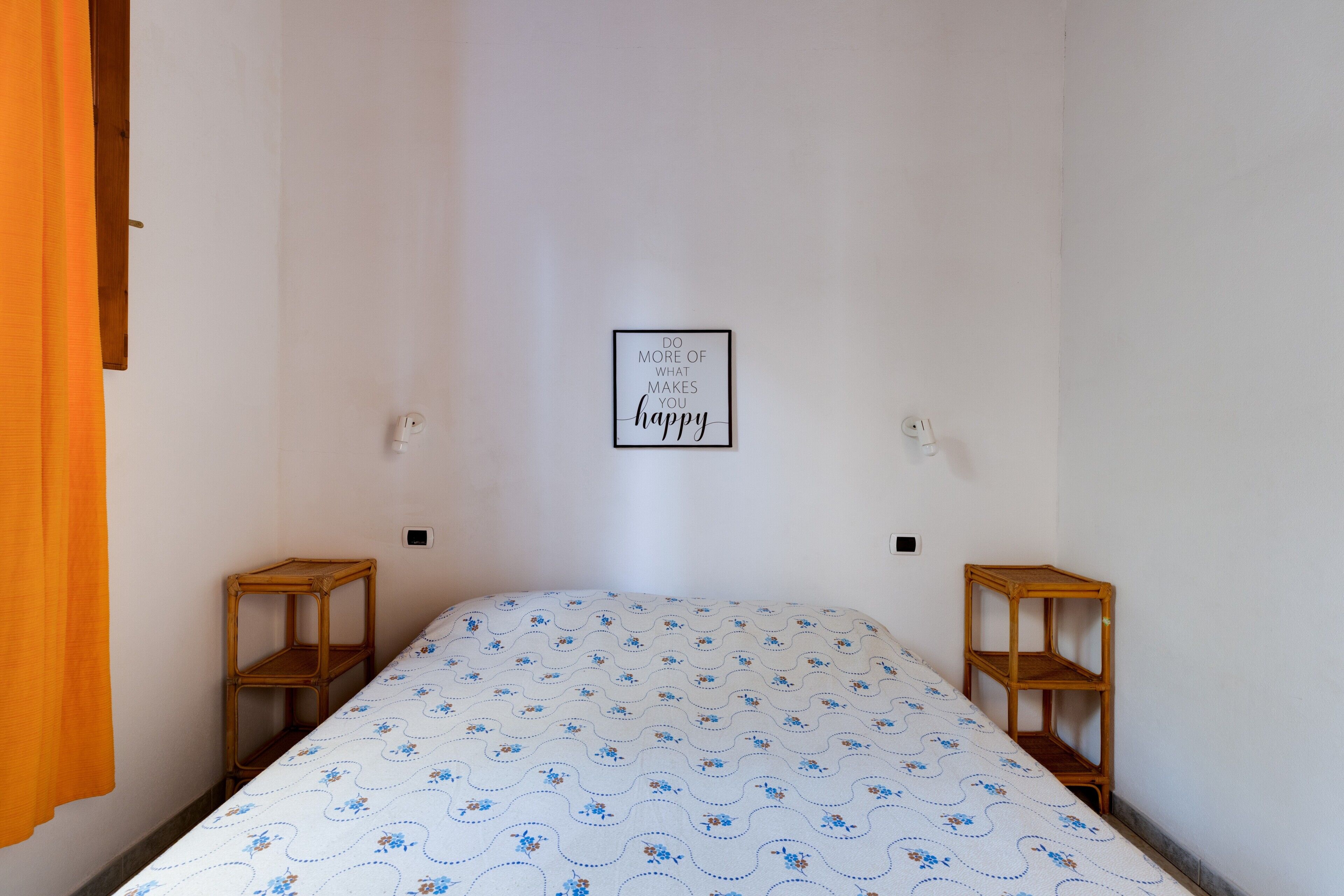 A room with a bed, two nightstands, a wall-mounted light, and a motivational quote.