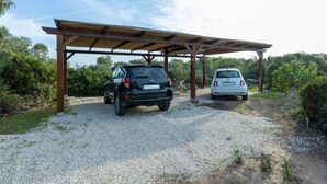 A covered parking area with two cars parked under a wooden structure. - Holiday Home "Samarighouse" close to the Sea with Garden & Wi-Fi (Sa Rocca Tunda)