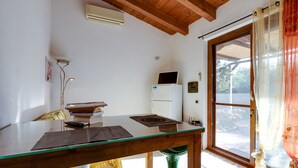 A room with a wooden ceiling, a glass table, a white refrigerator, and a window with a view. - Holiday Home "Samarighouse" close to the Sea with Garden & Wi-Fi (Sa Rocca Tunda)