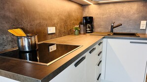 A modern kitchen with a built-in stove, a sink, and a coffee maker. - Apartment "Duregger App Sonnenschein" with Mountain View, Garden & Wi-Fi (Sand in Taufers)
