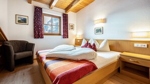 A bedroom with a bed, a chair, a nightstand, and a window with curtains. - Apartment "Duregger App Sonnenschein" with Mountain View, Garden & Wi-Fi (Sand in Taufers)