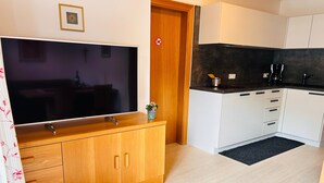 A modern kitchen with white cabinets, a large flat-screen TV, and a coffee maker. - Apartment "Duregger App Sonnenschein" with Mountain View, Garden & Wi-Fi (Sand in Taufers)