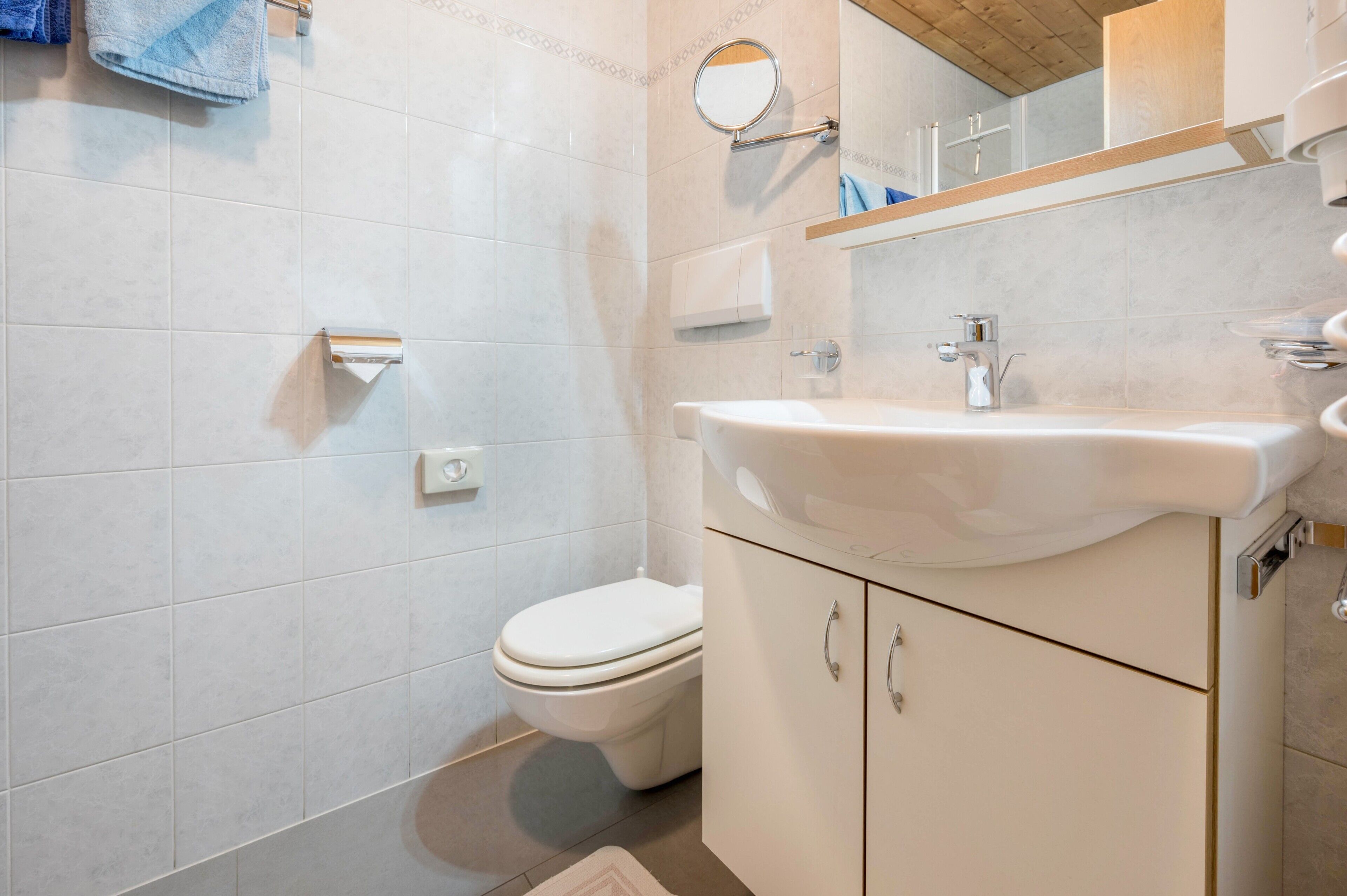 Et badeværelse med toilet, vask og spejl.