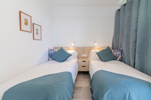 A bedroom with two beds, a wooden headboard, and a nightstand with a lamp.