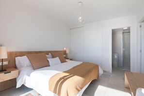 Une chambre à coucher avec une tête de lit en bois, un lit avec une literie blanche et marron, une table de chevet avec une lampe et un banc en bois.