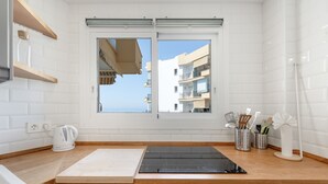 Eine moderne Küche mit einer Holzausziehtheke, einem eingebauten Herd und einem Fenster mit Blick auf Gebäude.