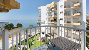 Ein Balkon mit Meerblick, einem Holztisch und einem weißen Geländer.