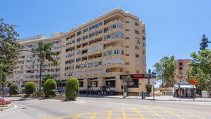 A multi-story hotel with balconies, a supermarket, and a small kiosk. - Apartment with Shared Pool, Sea View, Wi-Fi and Air Conditioning (Marbella)